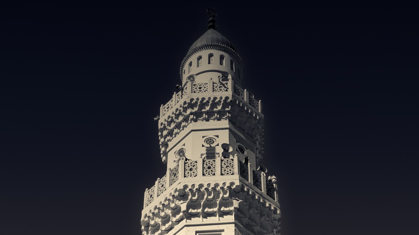 The white minaret of Quba Mosque, lit up against the night sky